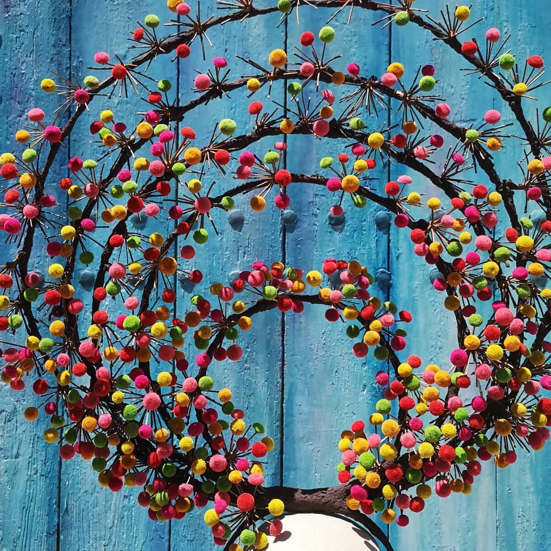 Circular multicoloured botanical sculpture on a blue background